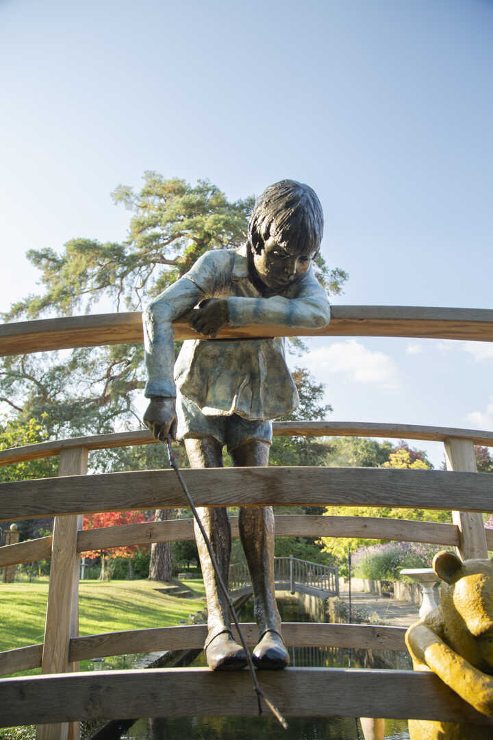 christopher robin playing poohsticks on a birdge with winnie the pooh